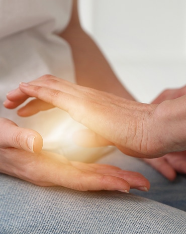 Reiki et Guérison Énergétique : Mains Lumineuses Mains tenant de l'énergie lumineuse dorée entre les paumes, symbolisant le Reiki, le soin énergétique ou la guérison par imposition des mains.